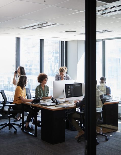 Creative business team working together in a casual office, seen through glass wall