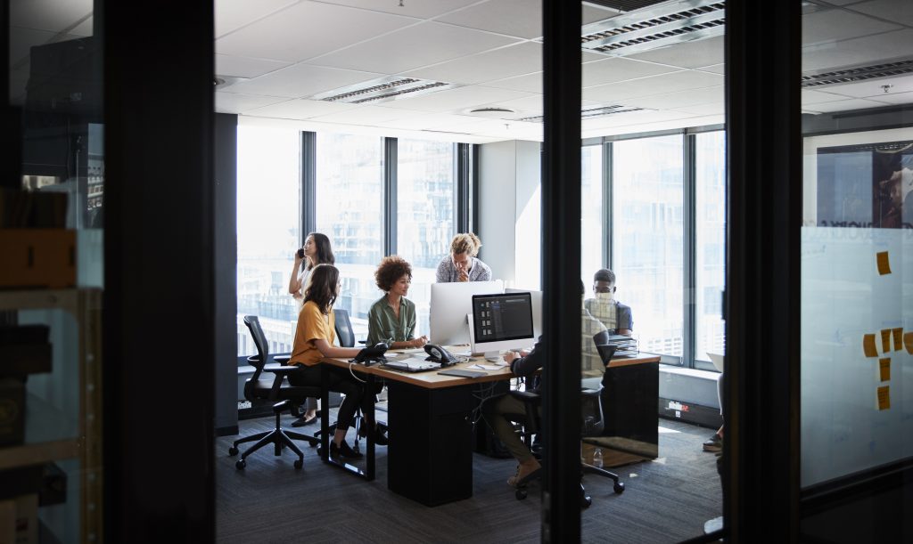 Creative business team working together in a casual office, seen through glass wall